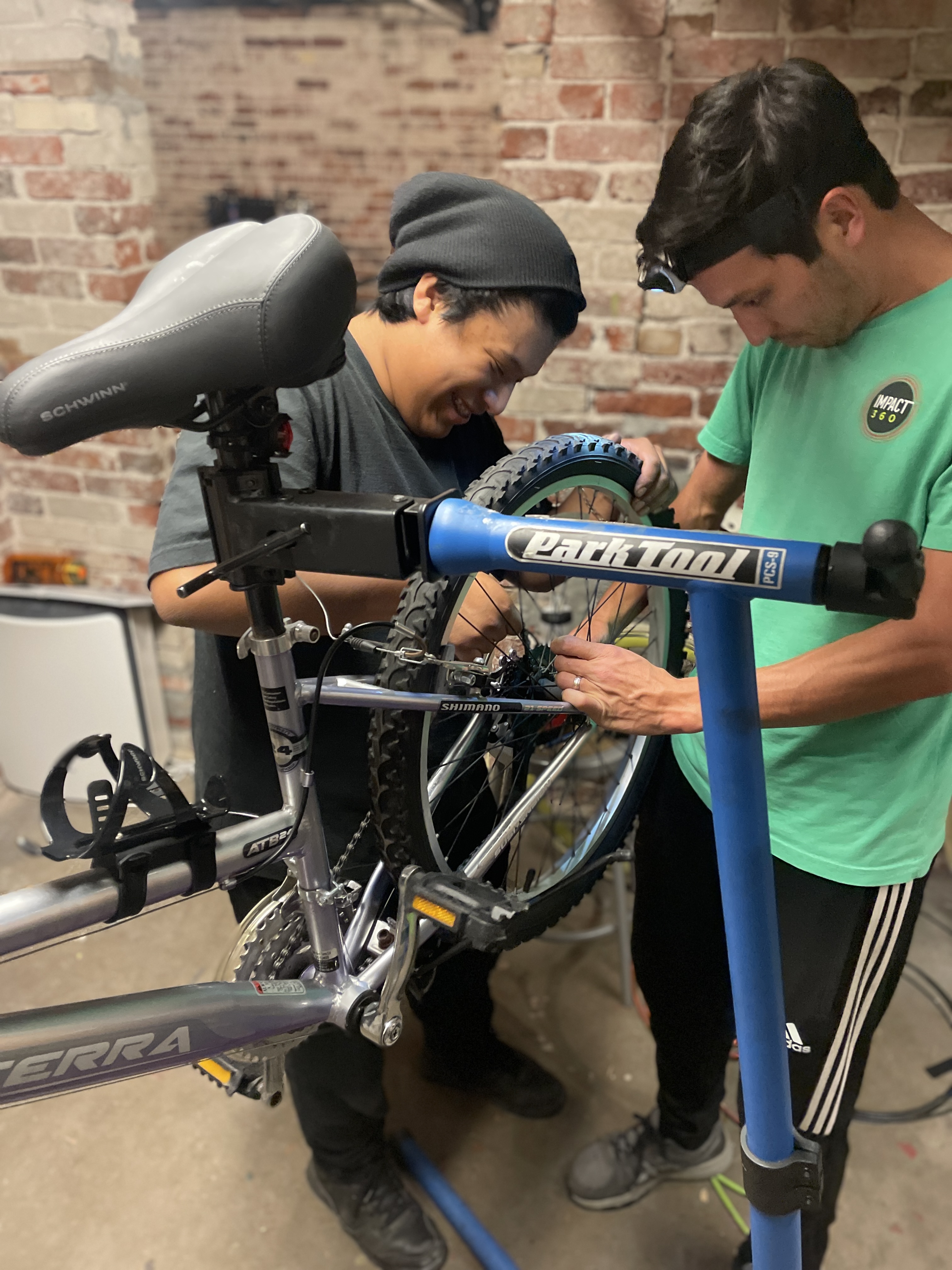 A student intern collaborates with a staff member on bike maintenance