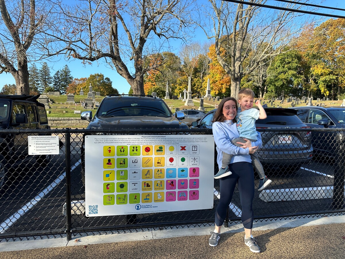 Harry and mom at the ribbon cutting ceremony for the reopening of the Beechwood Playground. Standing with the communication board, generously donated by the Flutie Foundation.