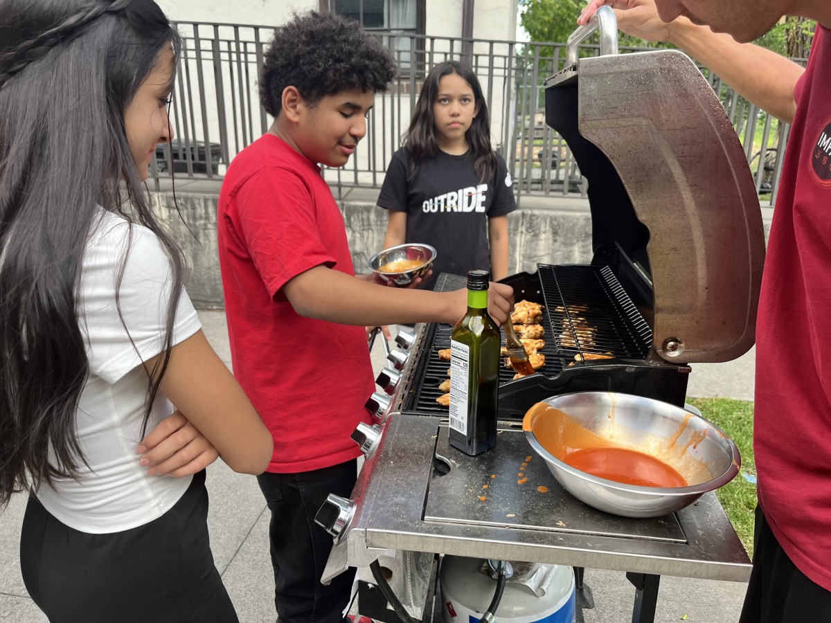 Armando grilling chicken wings during a Cooking Class