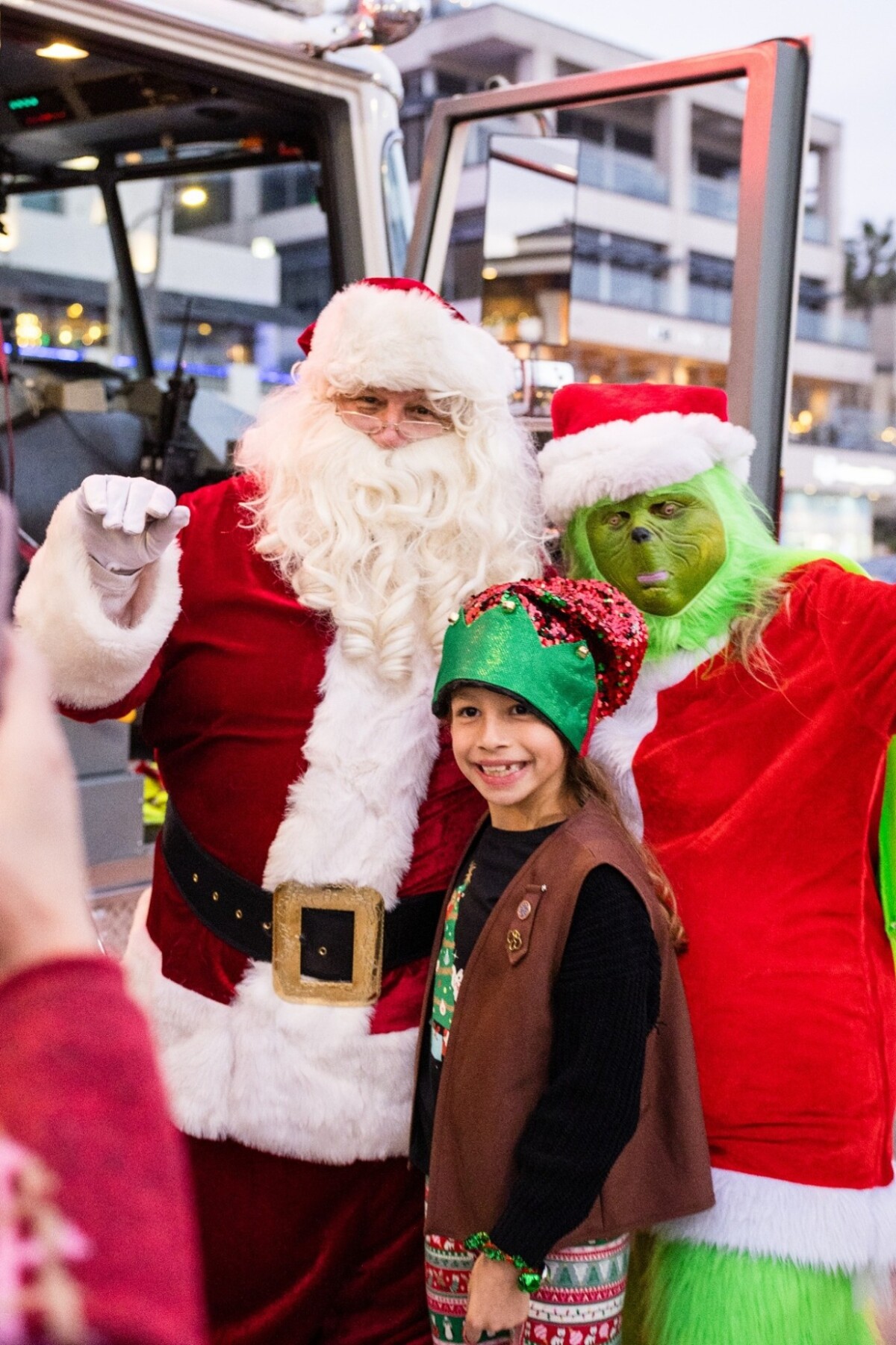 Santa and Grinch taking pictures with parade participant.